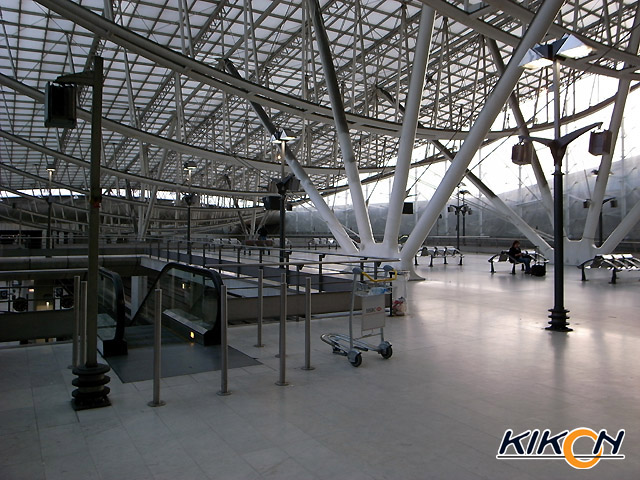 空港の駅構内、広いフロアに全く人影が見られない。逆アーチ構造の白色の鉄骨がガラス屋根を支えている