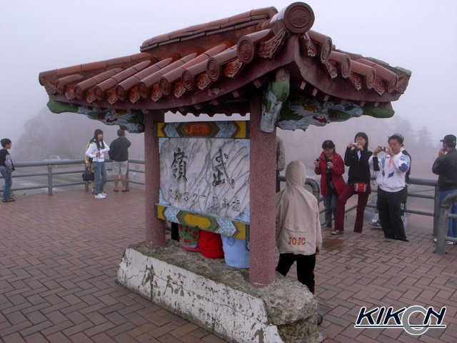 「武嶺」と彫られている石作りの表示板、中国風の瓦屋根がついている。その前では観光客が記念撮影をしている