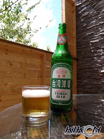テラスのテーブルにおかれた緑のボトルの台湾ビール、側のグラスにもビールが入っている。
