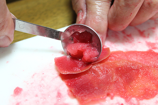 スプーンで皮についた果肉を削っている