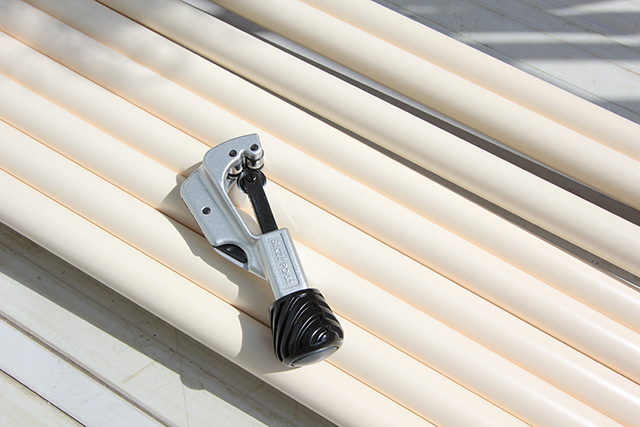 並べたパイプの上に置かれたパイプカッター