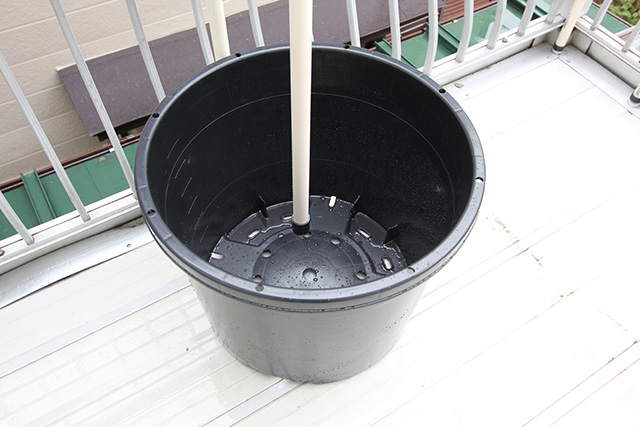 ベランダに置かれた黒いポットの中に支柱が立てかけてある