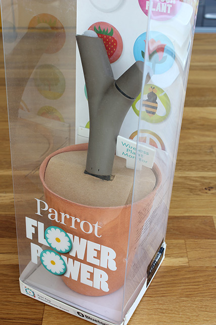 「Parrot Flower Power」とかかれた透明な箱の中、木の枝の形の端末が植木鉢を模した台座に刺さっている