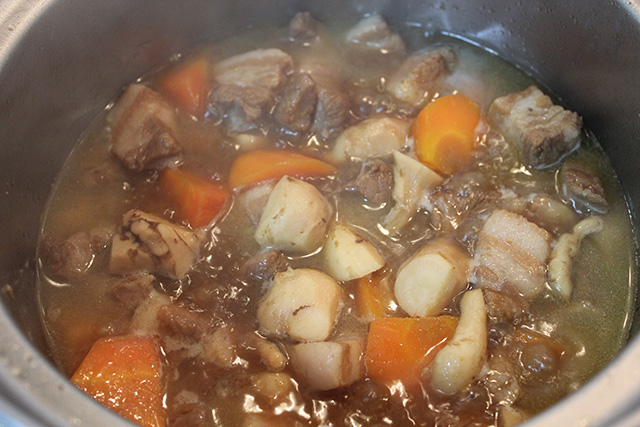 鍋の中で、豚バラ肉、ニンジンとともに煮られているシカクマメの芋