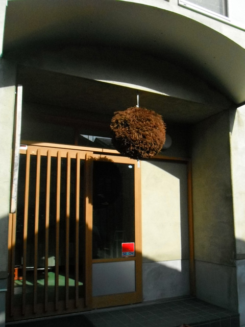 木の柵状の引き戸がある入口、茶色になった杉玉が吊るされている