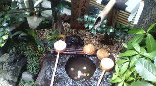 銭洗いの井　岩に掘られている穴に竹管から水が注がれる、周囲に柄杓が置かれている